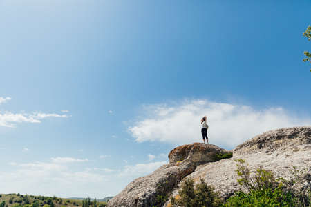 a beautiful woman looks at the view on top of a cliff on a cliff on a journeyの写真素材