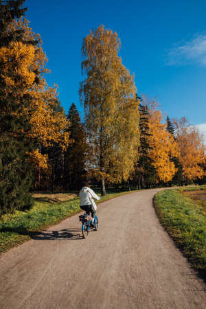 a woman rides a bicycle on a forest autumn roadの写真素材