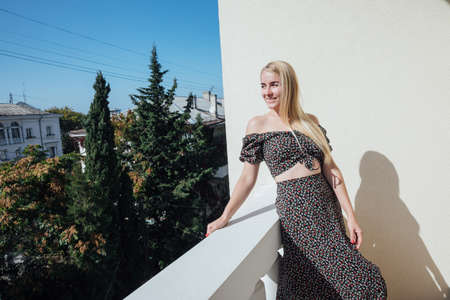 beautiful blonde woman in a gray dress looks from the balconyの写真素材