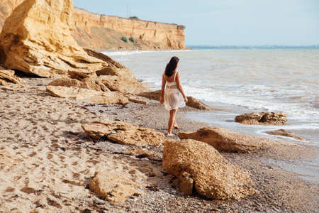 woman walking on a sandy beach by the sea wavesの写真素材