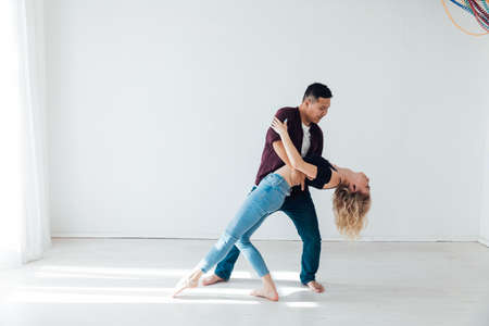 a man and a woman dance to the music of a paired dance of bachata in a white roomの写真素材