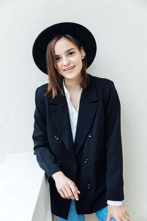portrait of a beautiful fashionable young woman in jeans and a black hatの写真素材