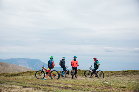 mountain bikers on top of the mountain look at the view on a journey