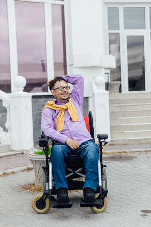 a man with a disability in a wheelchair on a walk on the streetの写真素材