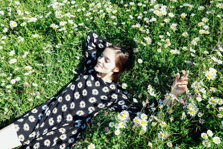 beautiful woman in a dress with flowers lies in the grass with daisiesの写真素材