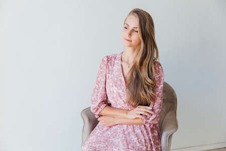 portrait of a beautiful blonde woman in a summer pink dressの写真素材