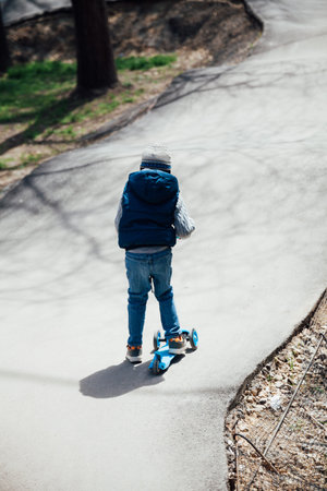 beautiful little boy riding a scooter on the street