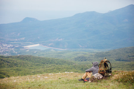 a man on top of a mountain looks at a beautiful landscapeの写真素材