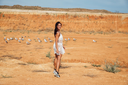 beautiful tanned woman in a summer dress in a clay desertの写真素材