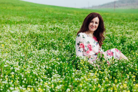 beautiful woman in a spring dress in a blooming garden with green grass