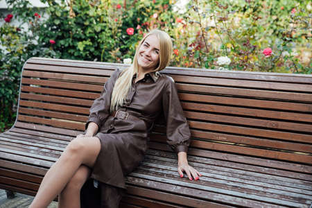 beautiful blonde woman in a raincoat on the street of the city walkの写真素材