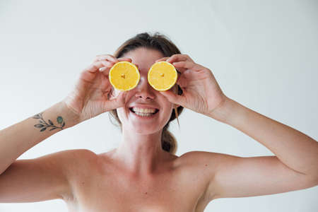 portrait beautiful fashionable blonde woman holding yellow lemons in her handsの写真素材