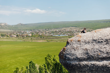 woman traveler looks at the landscape from the top of the mountain