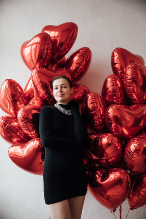 beautiful woman in black dress with red balloons for the holidayの写真素材