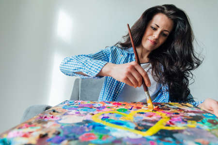 beautiful woman artist paints a picture with colored paintsの写真素材