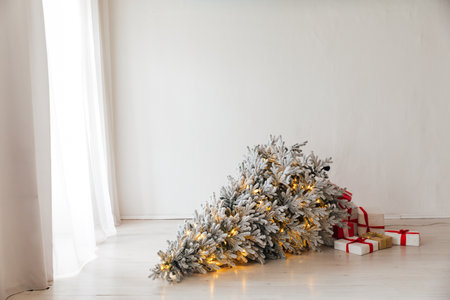 Christmas tree with garlands lies on the floor in the room with gifts new year decorationsの写真素材