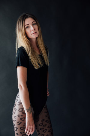 woman in a black swimsuit bodysuit poses on a black backgroundの写真素材