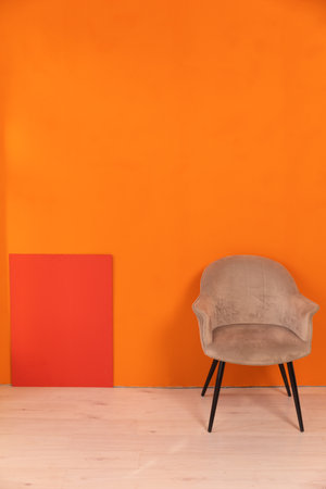 a gray armchair against the orange wall in the room interiors as backgroundsの写真素材