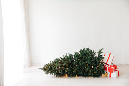 Decorated Christmas tree fallen down. Christmas gifts near fallen tree. Scandinavian Christmas tree.の写真素材