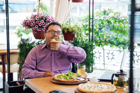 a man eats pizza in a restaurant pizzeria food fast foodの写真素材