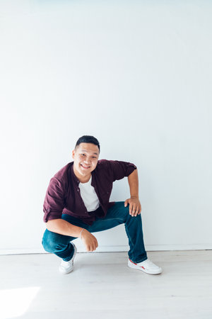 brunette man squatting in a bright roomの写真素材