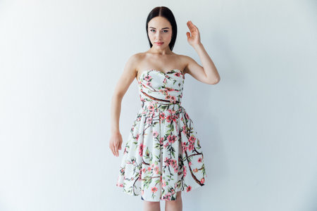 beautiful woman in a floral dress posing in a bright roomの写真素材