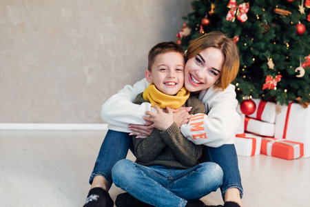 mother and son sit by the tree with gifts New Year Christmasの写真素材