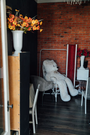 a large soft toy in a chair in a room with flowersの写真素材