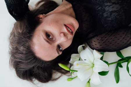 beautiful brunette woman lies with a flower in a bright roomの写真素材