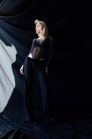 a fashionable woman in black clothes stands on a black backgroundの写真素材