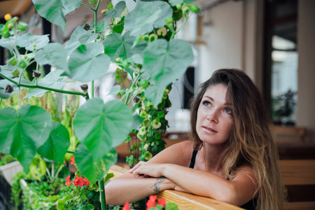 a woman sits in a restaurant on a veranda outside waiting for foodの写真素材