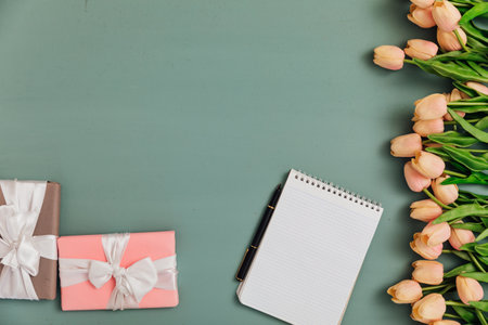 tulip flowers on a painted blue background with gifts and a notebook for the holidayの写真素材