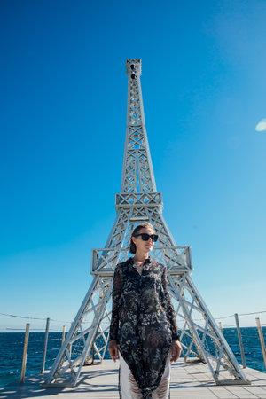 a woman stands by the sea near the Eiffel Towerの写真素材