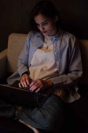 remote work woman with laptop via internet conversation online in a dark roomの写真素材
