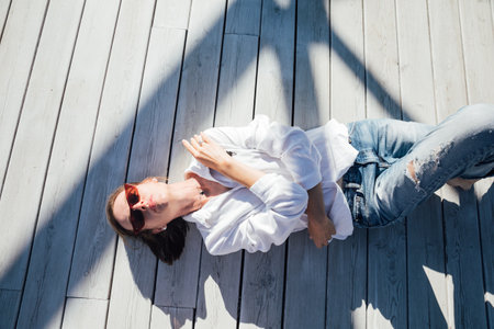 a woman lies on a wooden floor walking outsideの写真素材