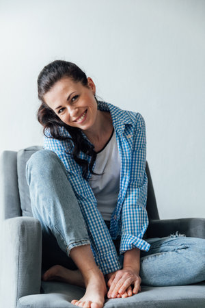 a woman in denim sitting in a chair in a bright roomの写真素材