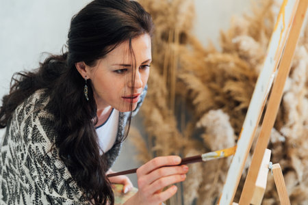 a woman artist stands at an easel with a palette of art drawingの写真素材