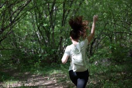 a woman with a backpack walks on the road in the woods hiking journey on footの写真素材