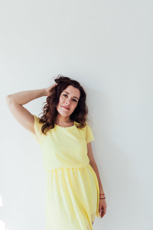 a beautiful woman in yellow clothes stands in a bright roomの写真素材