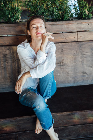 a beautiful woman sitting against a wooden wallの写真素材