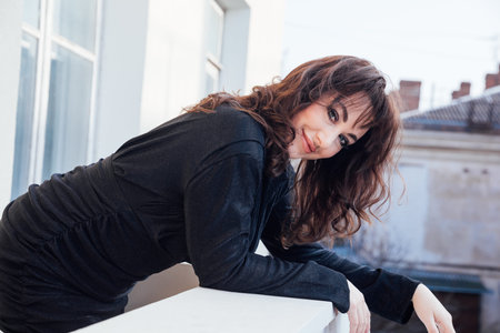 a woman in a black dress stands on the balcony in the roomの写真素材