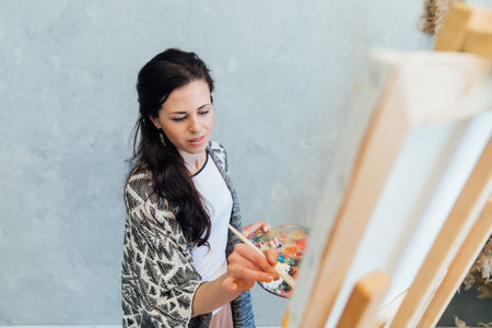 female artist draws with a brush using a palette on an easel in an art studio teacherの写真素材