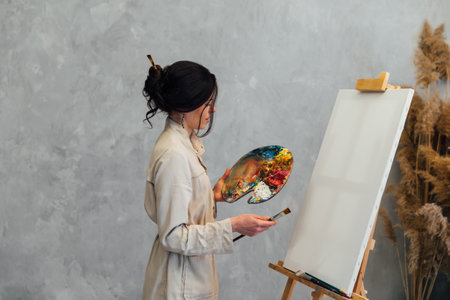 the artist stands with a palette and brushes at the easelの写真素材