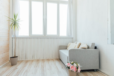 grey sofa with cushions and flowers in a bright room interior furnitureの写真素材