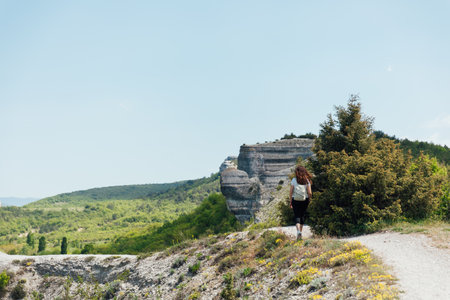 woman on a hike with a backpack walk on the mountain of rocks nature walks along the roadの写真素材