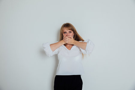 a woman in white covered her mouth with her hands does not speak silentの写真素材