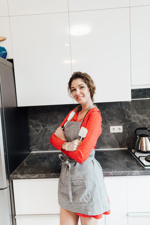 a housewife in an apron stands by a metal bowl in the kitchenの写真素材