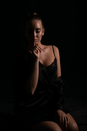 a woman in a black shirt shows a sign of silenceの写真素材