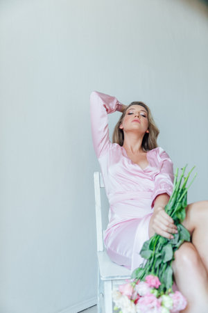 Delicate woman in pink dress with bouquet of flowersの写真素材