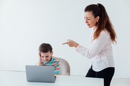 Woman talking to boy at table with laptopの写真素材